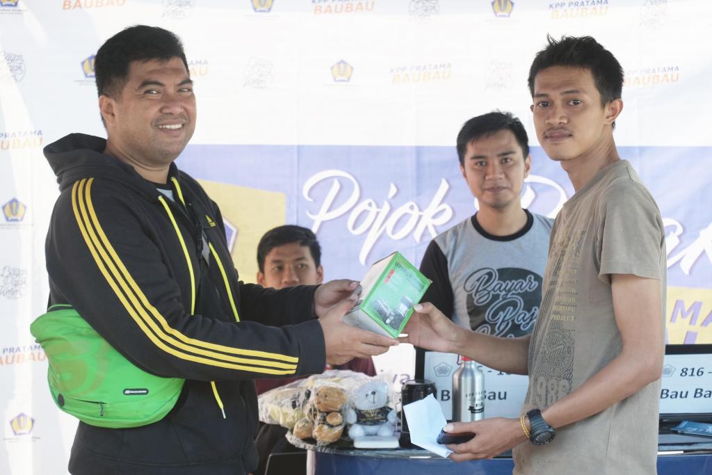 Kepala Subbagian Umum dan Kepatuhan Internal KPP Pratama Baubau menyerahkan souvenir kepada wajib pajak yang telah melaporkan SPT Tahunan