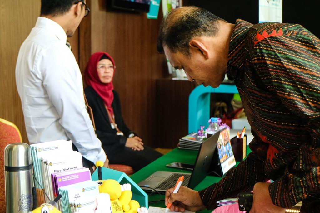 Salah satu peserta kegiatan sedang mengisi buku tamu setelah berkonsultasi dengan petugas
